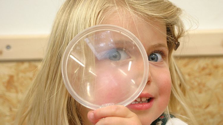  Kita: Ein Kind schaut neugierig durch eine Lupe (Foto: Meyborg)