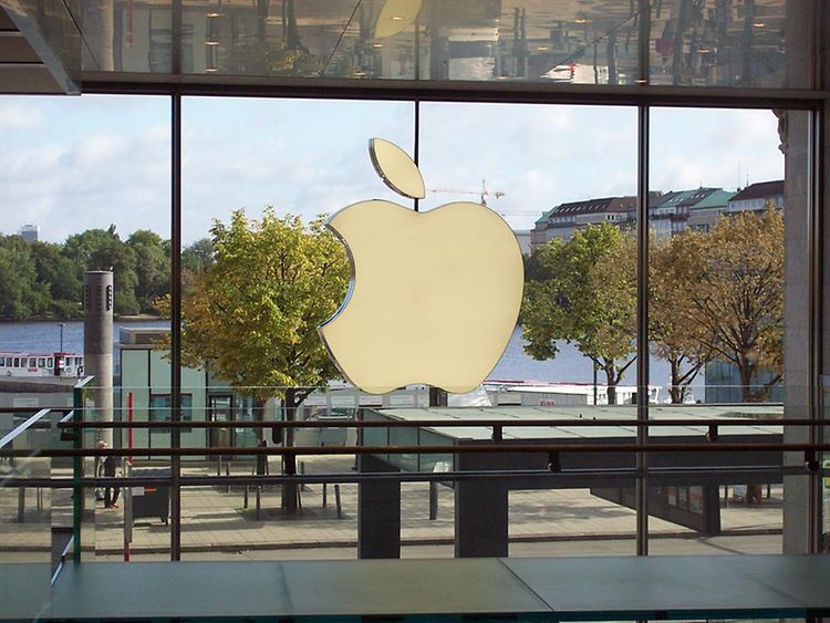  Ein goldener angebissener Apfel ist das Logo von Apple, das hier an einer Glasfassade angebracht ist.