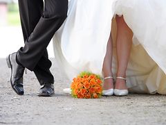  Beine eines Hochzeitspaares, dazwischen ein Blumenstrauß auf dem Boden