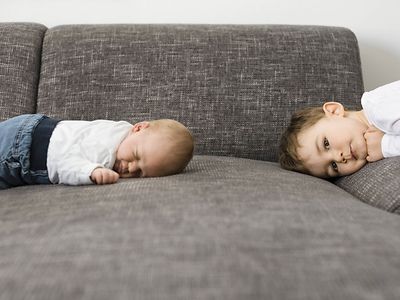  Zwei Kinder liegen auf dem Sofa
