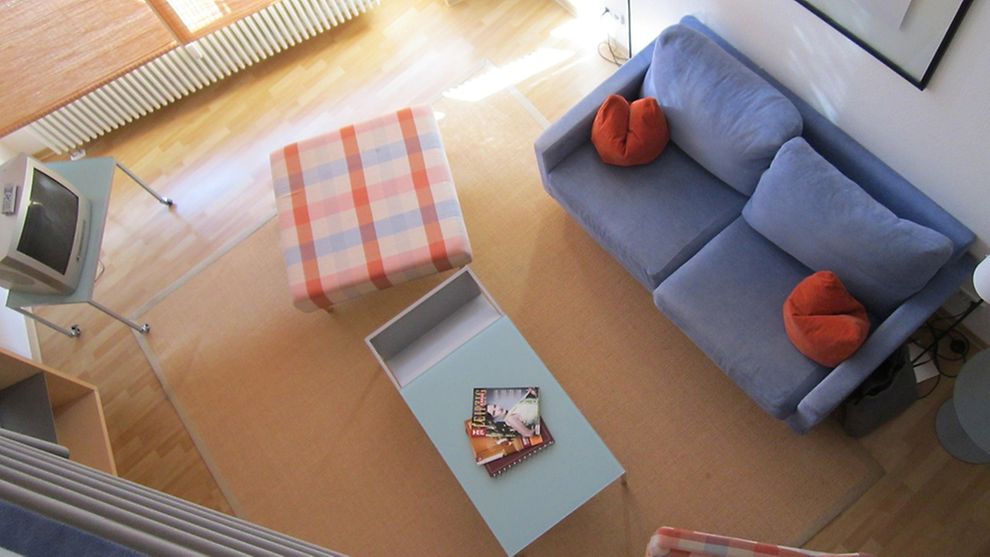 Möbliertes Wohnzimmer mit Sofa, Bild über dem Sofa und kleinem Glastisch