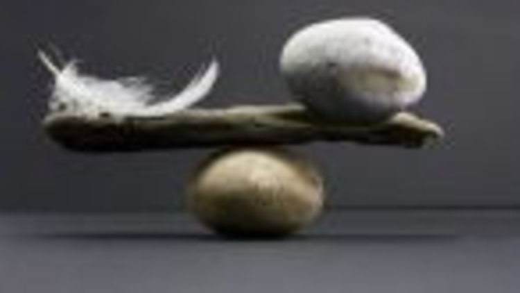  Steine, ein Ast und eine Feder symbolisieren das Gleichgewicht in Form einer Waage