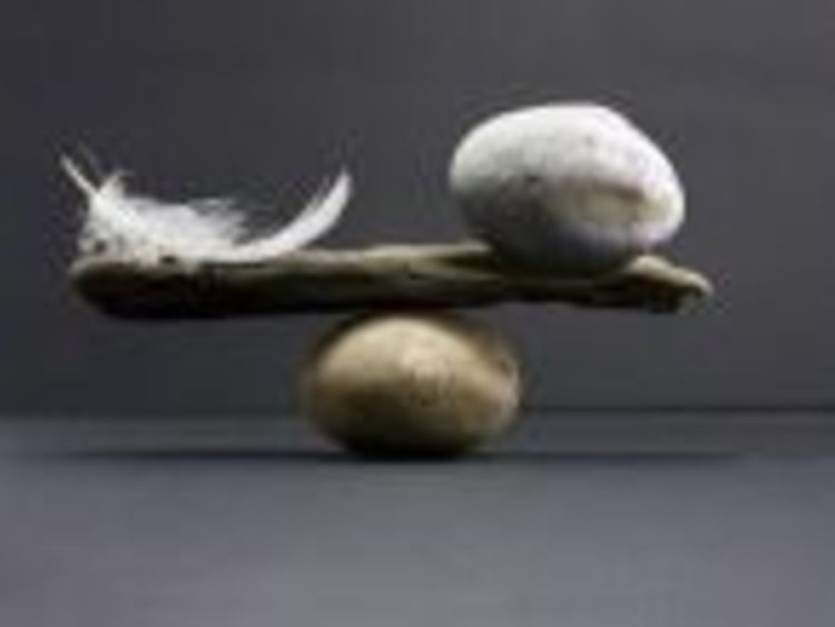  Steine, ein Ast und eine Feder symbolisieren das Gleichgewicht in Form einer Waage