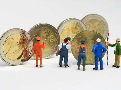  Geldmünzen davor Arbeiter-Modelle, die kleiner als die Münzen sind