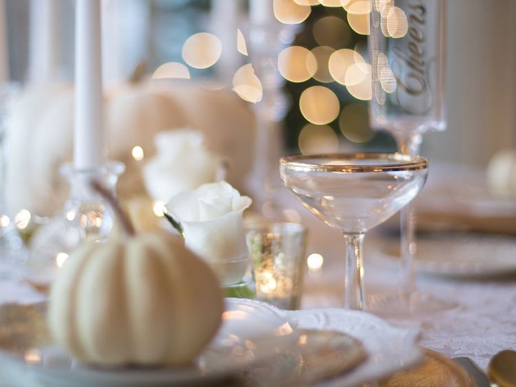  Ein Tisch ist mit goldenen Akzenten gedeckt und dekoriert, im Hintergrund funkeln Lichter.
