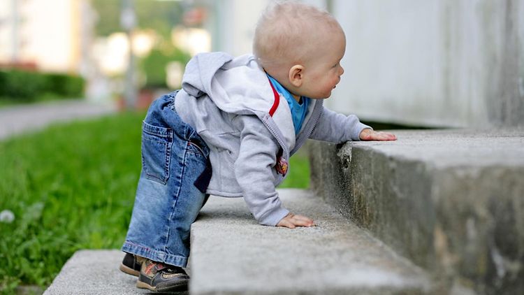  Ein Kleinkind krabbelt Stufen hoch