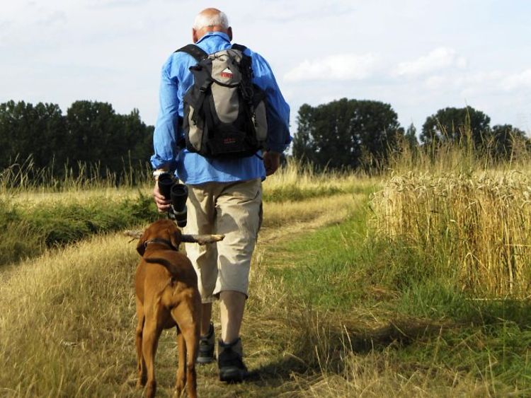  Älterer Mann mit Hund beim Wandern