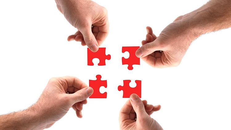  Puzzleteile , die von mehreren Händen zusammengesetzt werden