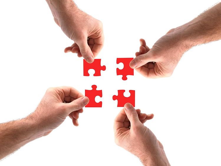  Puzzleteile , die von mehreren Händen zusammengesetzt werden