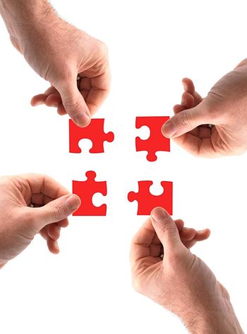 Puzzleteile , die von mehreren Händen zusammengesetzt werden