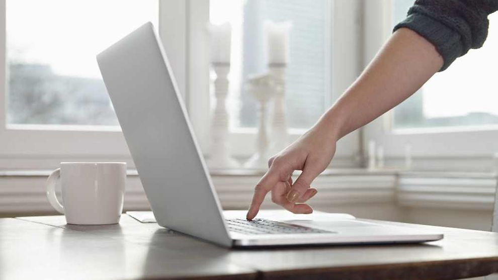 Eine Frau tippt mit dem Zeigefinger auf die Tastatur eines Laptops