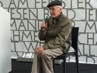  Ludwig Baumann sitzt draußen in einem Zelt vor dem Mikrofon