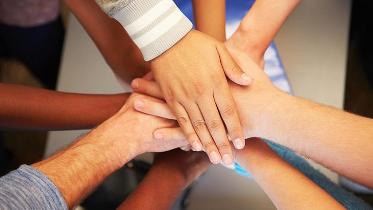  Hände junger Menschen verschiedener Hautfarben miteinander verbunden