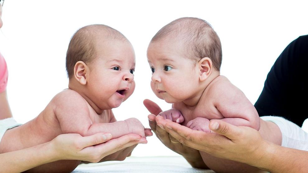 Zwei Babys getragen auf Händen