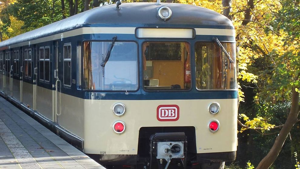  Eine historische S-Bahn in der Farbe creme fährt in eine Station ein