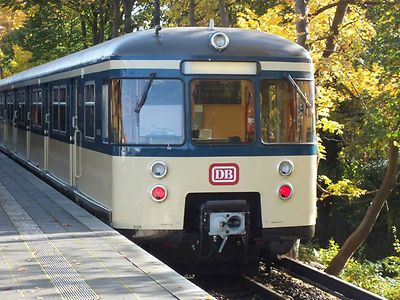  Eine historische S-Bahn in der Farbe creme fährt in eine Station ein