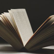  Eine Nahaufnahme eines aufgeschlagenen Buches vor schwarzem Hintergrund.