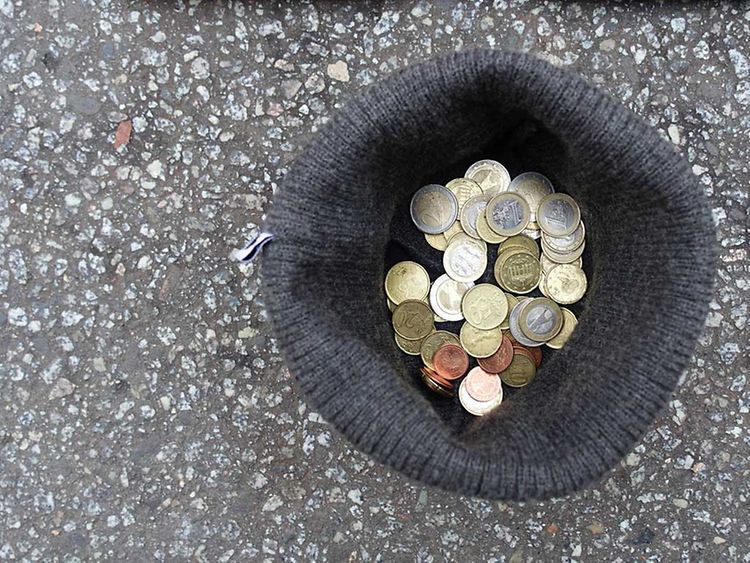  Eine Mütze auf der Straße mit Eurostücken, die gespendet wurden