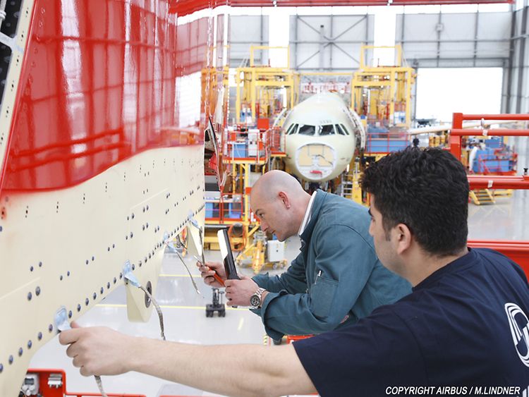  Zwei Airbus-Mitarbeiter arbeiten an einem Flugzeugteil
