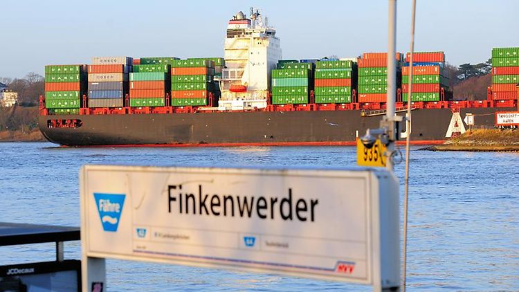  Schild des Fähranlegers Finkenwerder mit einem Containerschiff im Hintergrund