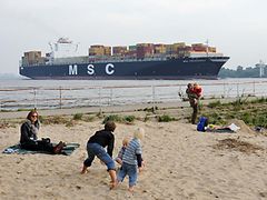  Kinder beobachten am Rissener Ufer ein vorbeifahrendes Containerschiff