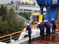  Arbeiter an Deck, im Hintergrund ein blau-gelber Kran von Blohm+Voss