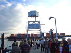  Besucher des Willkomm Höft beobachten ein Containerschiff auf der Elbe