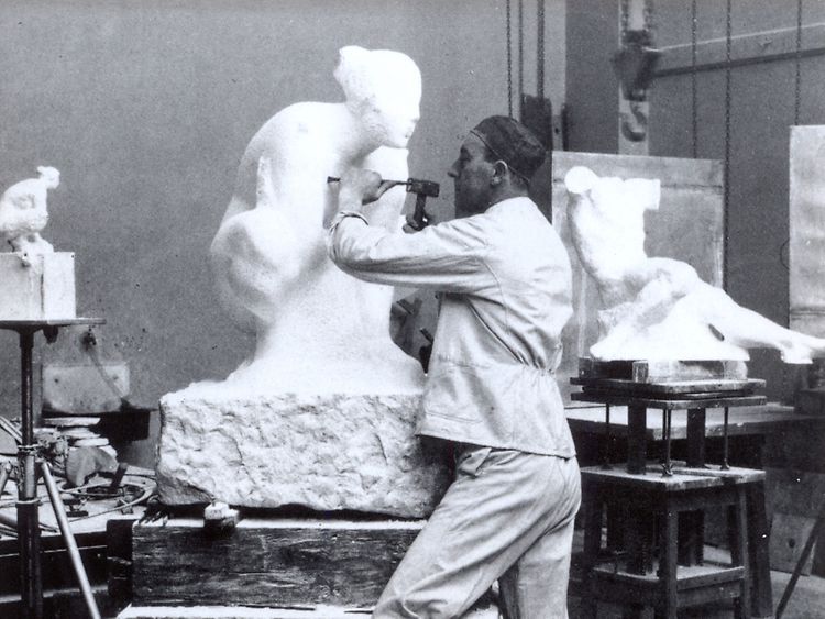  Mann arbeitet mit Hammer und Meißel an der Skulptur einer Frau