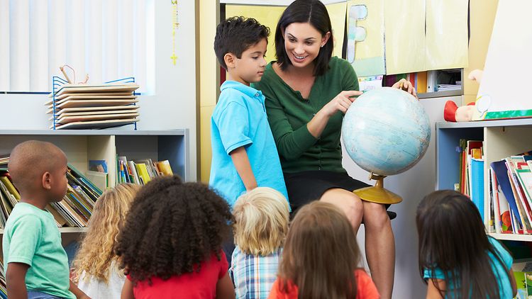  Lehrerin zeigt einem Schüler etwas auf einem Globus