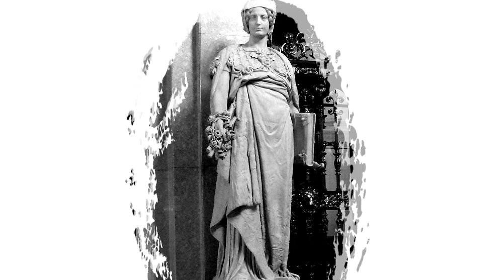 Eine Marmorfigur (eine Frau), die eine Robe trägt und ein Buch in der Hand hält.