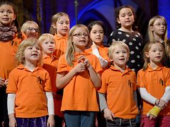  Kinderchor singend in leuchtend orangefarbenen T-Shirts
