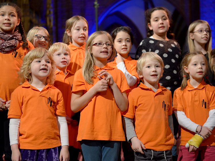 Kinderchor singend in leuchtend orangefarbenen T-Shirts