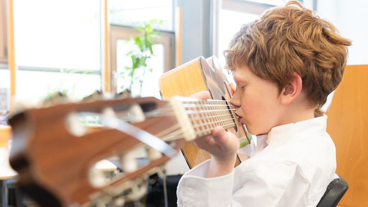  Therapie: Schüler erzeugt durch das Blasen in den Hohlraum Töne auf einer Gitarre