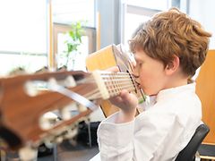  Therapie: Schüler erzeugt durch das Blasen in den Hohlraum Töne auf einer Gitarre