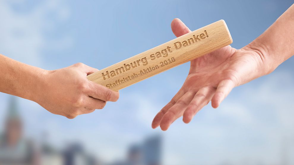  Übergabe eines Staffelstabes mit der Aufschrift "Hamburg sagt Danke!"