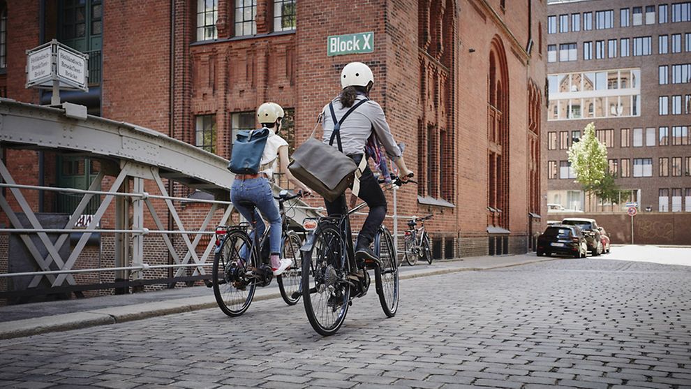 Zwei Fahrradfahrer*innen in der Hamburger Speicherstadt. 